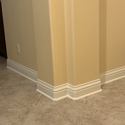 Detailed white baseboard trim wrapping an interior column